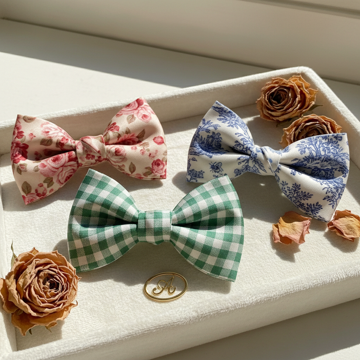 Signature silk hair bows in rose floral, green gingham, and blue toile bee prints on ivory velvet tray